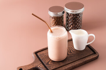 Freshly made milkshake or coffee with milk in a modern beer can-shaped glass on a wooden cutting...