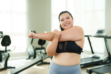 Beautiful overweight Asian woman does light exercise by stretching her arms and twisting her arms...