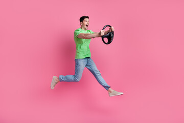 Full body photo of crazy automobile driver wear green t shirt drive fast speed vehicle steering wheel isolated on pink color background - obrazy, fototapety, plakaty