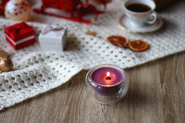 Various colorful Christmas decorations, soft blanket, cup of tea, sweet snacks and lit candles on the table. Cozy Christmas atmosphere at home. Selective focus.