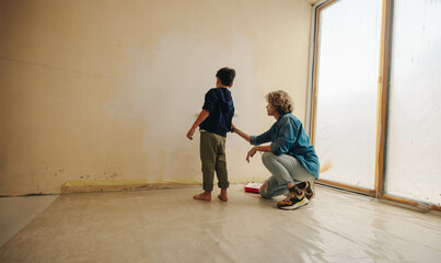 Family home renovation: Mother and son painting the wall for home improvement in the living room
