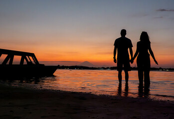 Couple holding hands at sunset on a tropical island by the ocean