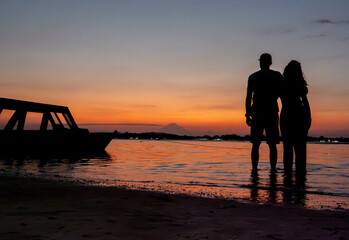 Couple holding hands at sunset on a tropical island by the ocean