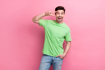 Portrait of young guy shows v sign green t shirt enjoying new postal company with five percent discount isolated on pink color background