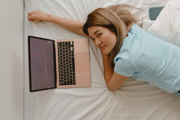 Back side and top view of asian woman using laptop, showing white empty screen, looking at camera...