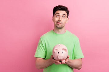 Photo of young man thinking hold piggy bank looks interested choosing what he could buy with...