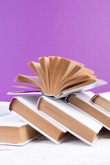 Open books, hardback colorful books on wooden table. purple background. Back to school. Copy space for text. Education business concept.