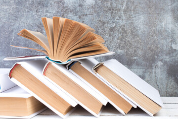 Open books, hardback colorful books on wooden table. gray concrete background. Back to school. Copy space for text. Education business concept.