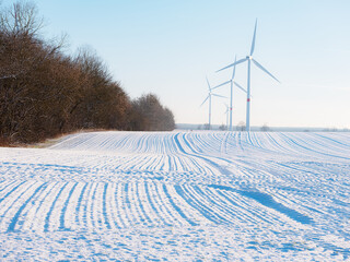 Fototapeta na wymiar Wind turbines and agricultural field on winter day.