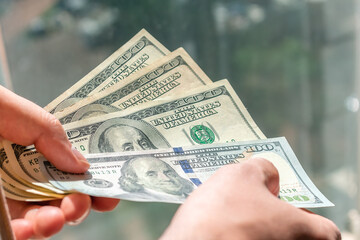 One hundred dollar bills in the hands of a white man. A man holds hundred dollar bills in his hands.