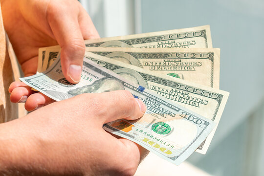 One hundred dollar bills in the hands of a white man. A man holds hundred dollar bills in his hands.