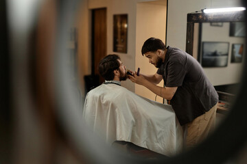 Young professional barber working with customer in barber shop