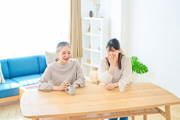 部屋で仲良く話すシニア女性と若い女性