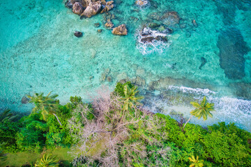  Bird eye drone of Port Glaud beach, granite stones, white sandy beach, turquoise water, coconut palm, greenery, trees, sunny day, Mahe Seychelles