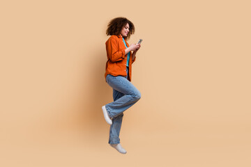 Fototapeta na wymiar Full length photo of adorable cute girl dressed trendy clothes using iphone reading sms isolated on beige color background