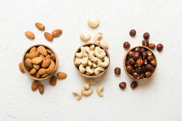 Assortment of nuts in wooden bowl on colored table. Cashew, hazelnuts, walnuts, almonds. Mix of nuts Top view with copy space
