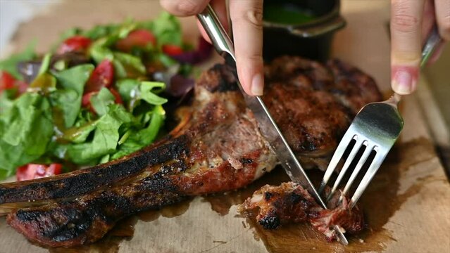 Woman eating beef stake at a restaurant with vegetables