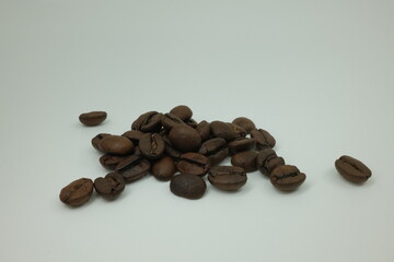 Pile of dark roasted espresso coffee beans on white background