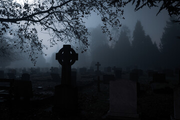 Spooky gravestones in a churchyard on a foggy winters mysterious night.