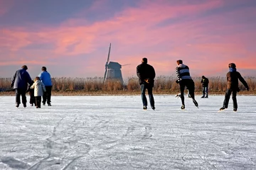 Fotobehang Ice skating at the windmill in the countryside from the Netherlands at sunset © Nataraj