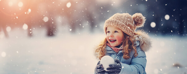 Cute girl standing in the natural park and holding a snowball in her hands.