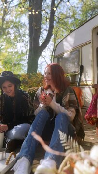 With their hippie vibe, the stunning young ladies sip their hot drinks in the midst of the yellow autumn foliage.