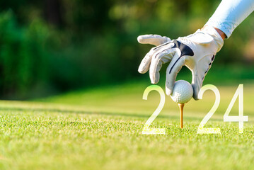 Close up hand Golfer woman putting golf ball for Happy New Year 2024 on the green golf for new healthy.  copy space. Healthy and Holiday Concept - obrazy, fototapety, plakaty
