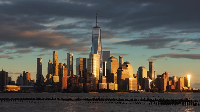 New York City skyline at sunset with World Trade Center skyscrapers from the Hudson River. Financial District of Lower Manhattan timelapse