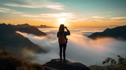 Young woman traveler taking photo with smartphone at sea of mist and sunrise over the mountain.