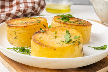 Potato fondant, tender potatoes with pucks close-up in a white plate.