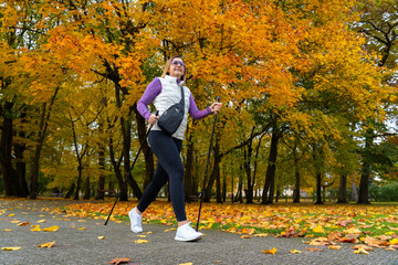 Nordic walking - mid-adult woman exercising in city park
