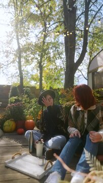 Embracing the autumn scenery, these charming young hippie girls take pleasure in their hot beverages.