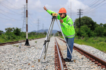 Engineer asian male wearing green uniform and orange hard hat use theodolite equipment and holdint...