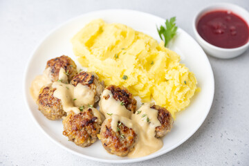 Swedish noisettes (fricandel) with mashed potatoes, Brune Sos creamy sauce and lingonberry (cranberry) sauce. Traditional meatballs with garnish. Selective focus, close-up.