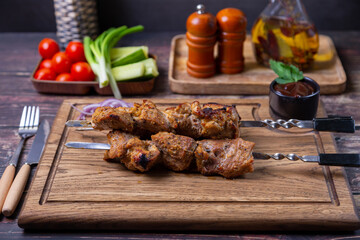 Traditional Russian shashlik on skewers with vegetables. Grilled pork meat (shish kebab). Close-up.