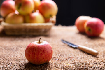 Ripe apples on burlap and in a basket on a black background. Rustic style, close-up.