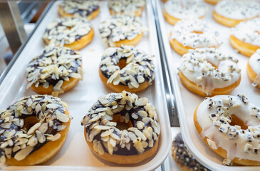 Assorted fresh donuts on display racks at the donut shop.Display of delicious pastries with assorted glazed donuts in shop.Various donuts on shelf in Bakery.Colorful flavor donuts with coating,topping