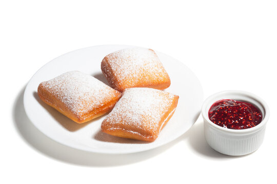 New Orleans Style Beignets, Fried Dough Fritters Topped with Powdered Sugar and Raspberry Sauce Isolated on White Background