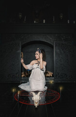 Fototapeta na wymiar Beautiful woman witch with horns hold mirror and make Halloween ritual
