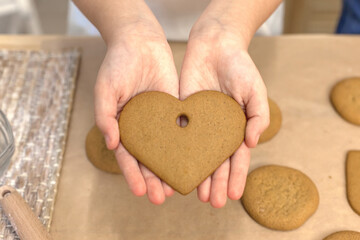 Process of making heart-shaped gingerbread for Valentine's Day. Cutting hearts out of dough with...