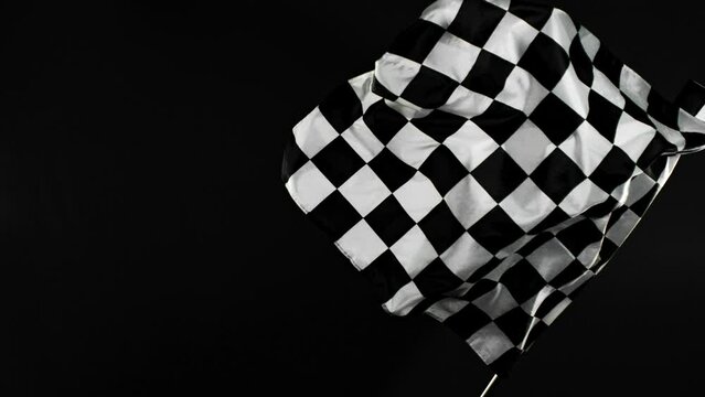 Super Slow Motion of Checkered Race Flag Waving Continuously in the Wind, 1000fps. Formula Racing Flag Isolated on Black Background. Victory, Achievement, Success and Sport Concept.