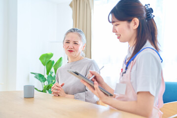 Obraz premium 会話するシニア女性とエプロン姿の若い女性