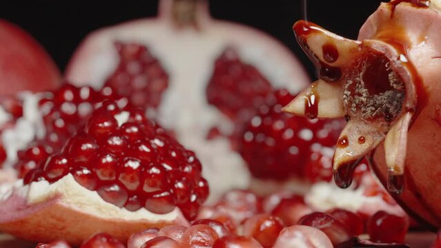 Red, Thick Sauce or Pomegranate Juice Drips from Above onto the Cleaned Pomegranate Fruits, Close-Up.