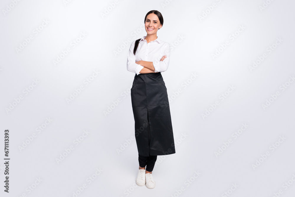 Sticker Full length body size photo of cheerful waitress with folded hands in black apron isolated on white color background