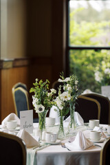 A wedding table setting with elegant looking vase of flowers.