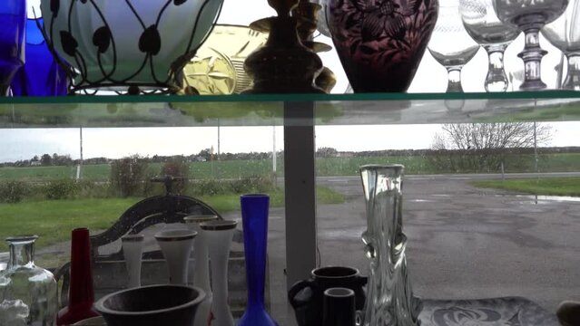 Lokken, Denmark Glassware on a shelf near a window for sale in an antique shop.