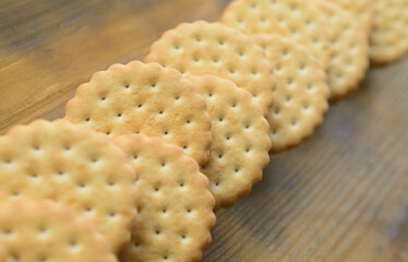 A round sandwich cookie with coconut filling lies in large quantities on a brown wooden surface. Photo of edible treats on a wooden background with copy space