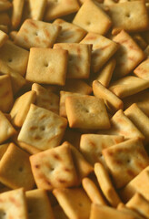 Background texture of small edible squares baked from dough and sprinkled with salt. A lot of salt cracker