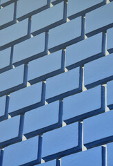 Decorative concrete wall with a relief similar to a large brick masonry painted in bright blue paint