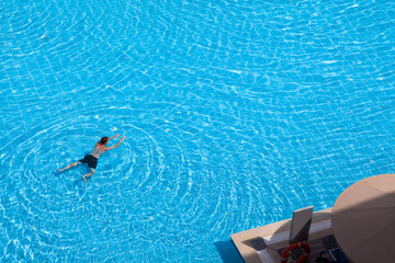 A young man swims in the pool, top view